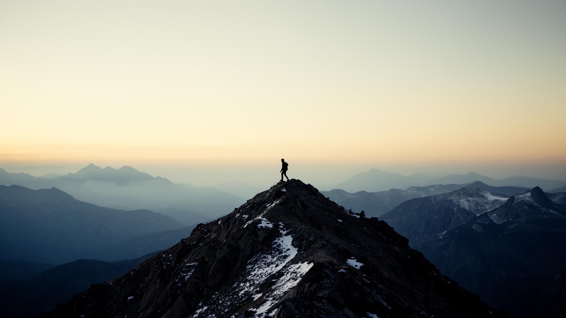 A lone figure on a high mountain ridgeline at dawn